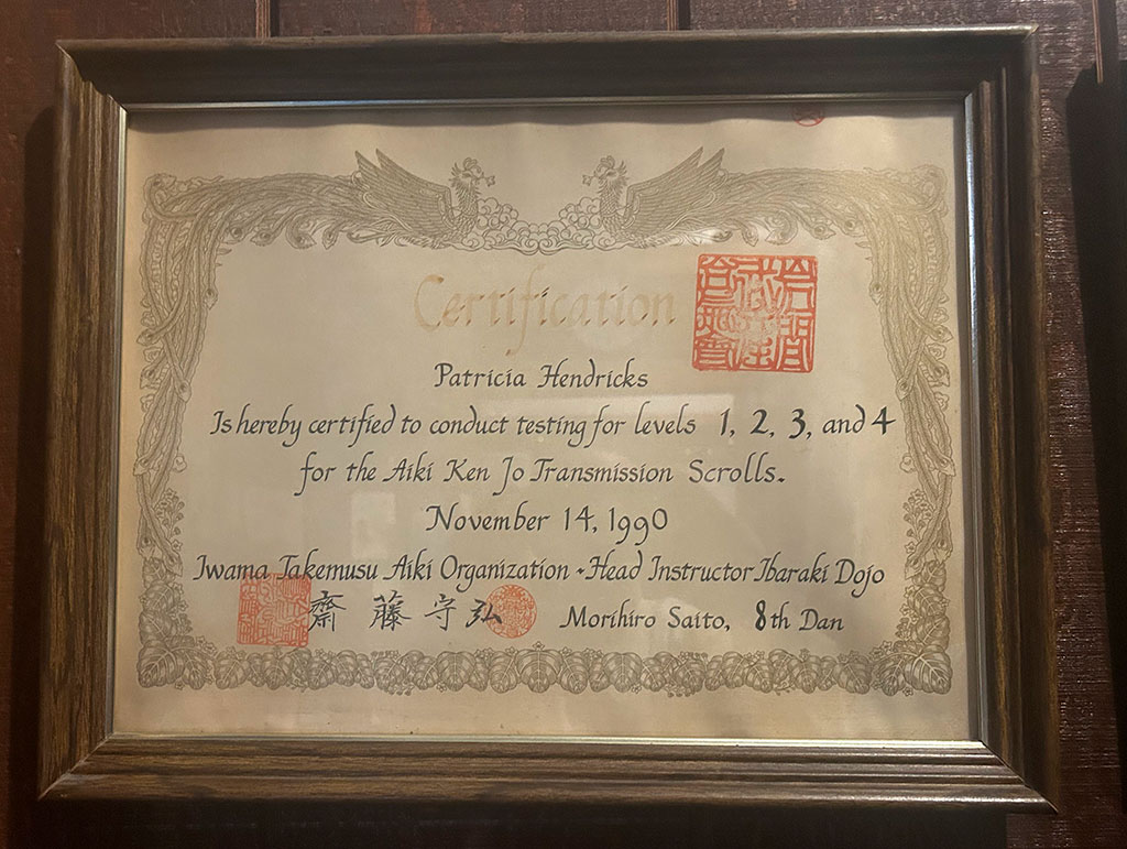 Certficate stating that Patricia Hendricks is entitled to direct examinations for the first to fourth scrolls of Aiki sword and staff. Issued in Iwama Takemusu Aiki on November 14, 1990, and signed by Saito Morihiro